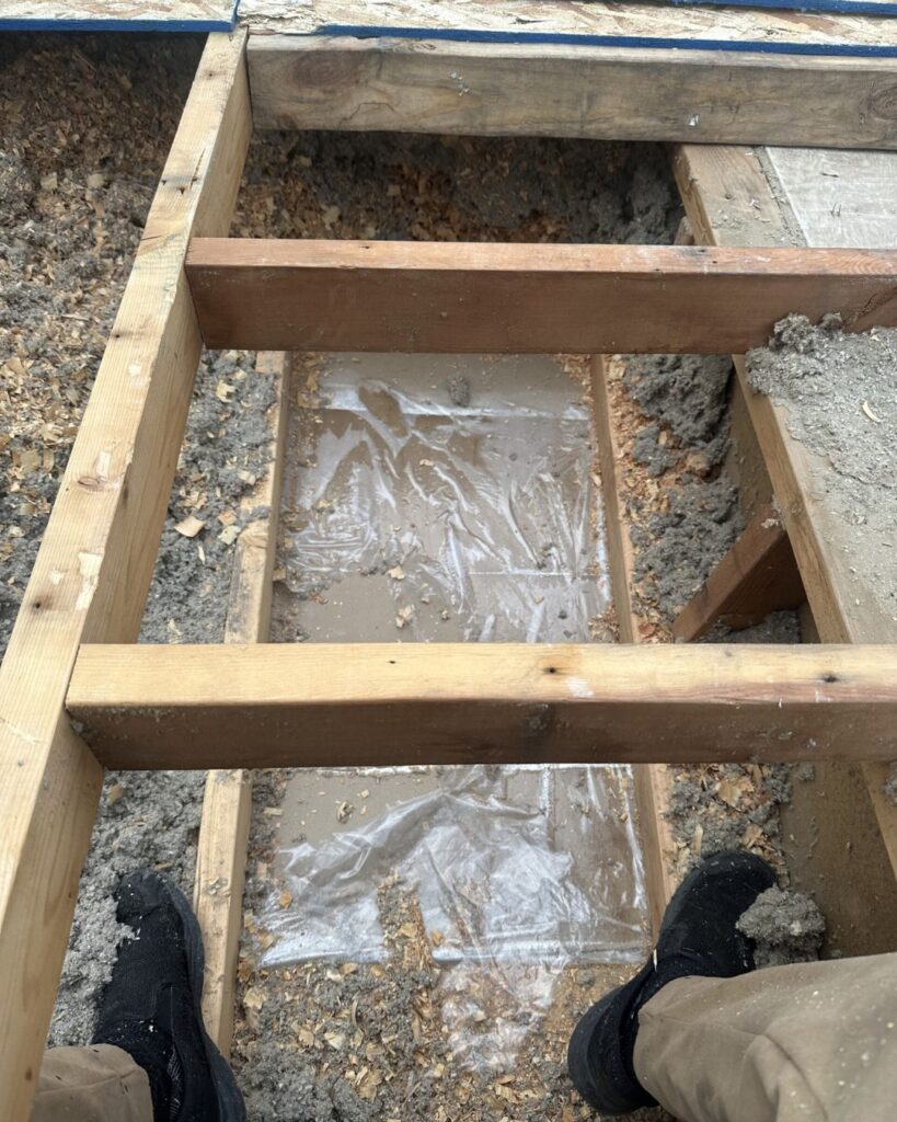 Standing water and saturated insulation between roof trusses exposed during a Calgary tear-off